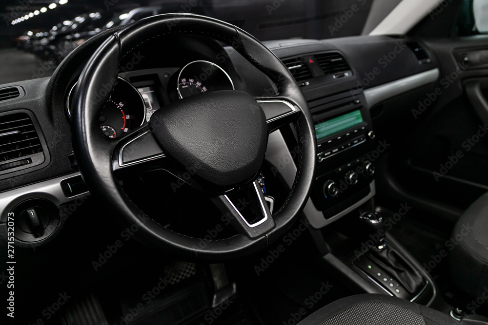 Close-up of the dashboard, speedometer, tachometer and steering wheel, dashboard. Luxurious car interior details.