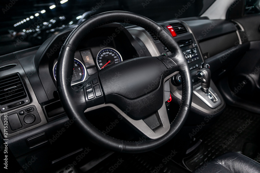Interior view of car with black salon. Modern luxury prestige car interior:, dashboard, speedometer, tachometer  with white backlight  steering wheel  with car controller system function..