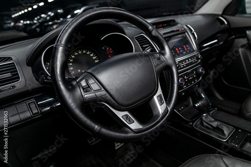 Interior view of car with black salon. Modern luxury prestige car interior:, dashboard, speedometer, tachometer with white backlight steering wheel with car controller system function.