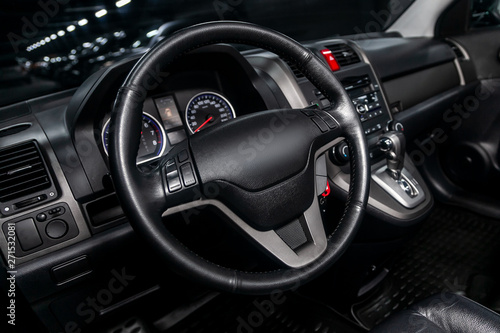Interior view of car with black salon. Modern luxury prestige car interior:, dashboard, speedometer, tachometer with white backlight steering wheel with car controller system function..