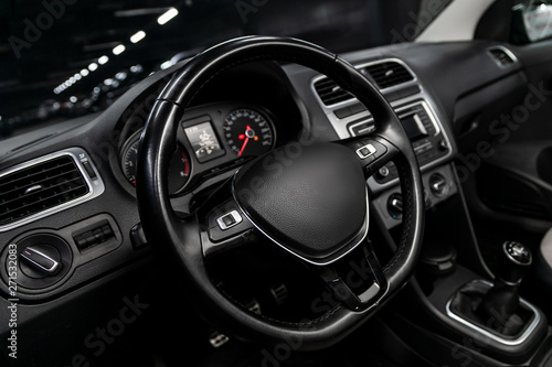 Interior view of car with black salon. Modern luxury prestige car interior:, dashboard, speedometer, tachometer with white backlight steering wheel with car controller system function.
