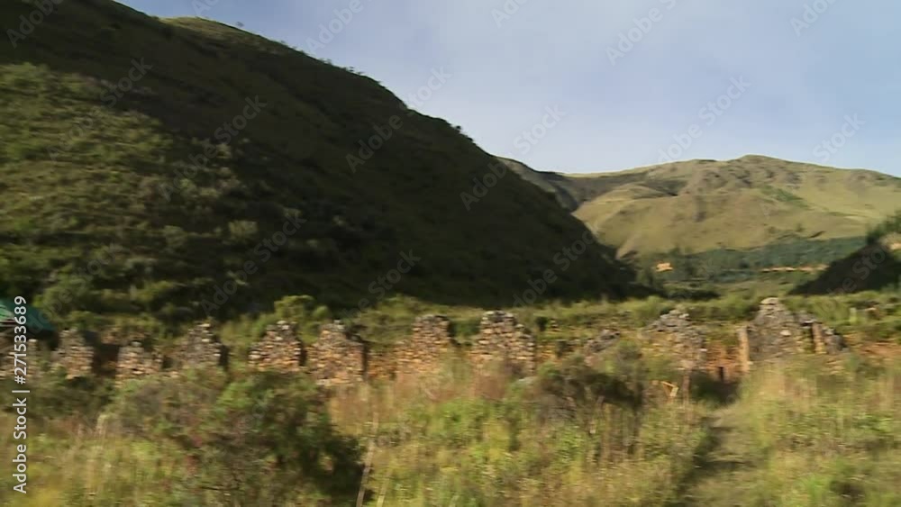 Steady, medium wide shot of a grassy hill with a wall made of stone in the foreground. Shot then pans to the right. Steady, medium wide shot of a grassy hill with a wall made of stone in the foreground. Shot then pans to the right.