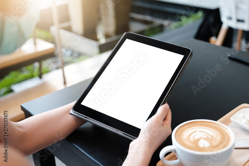Woman is showing digital tablet blank screen on work desk in coffee shop.