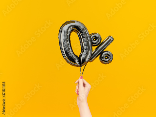 Female hand holding Zero percent symbol. 0 % offer black flying foil balloons on yellow. Loan rate fee concept. 3d rendering. photo
