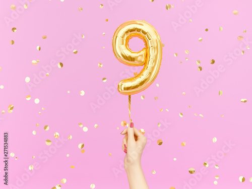 Nine year birthday. Female hand holding Number 9 foil balloon. Nine-year anniversary background. 3d rendering photo