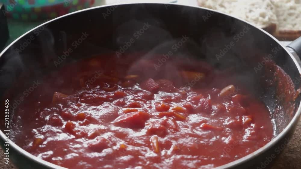 Super hot red tomato salsa sauce with a lot of steam comming of the round large cooking pot. Big spoon in the cooking pan with pure red colored salsa with lots of warm steam. Super hot red tomato salsa sauce with a lot of steam comming of the round large cooking pot. Big spoon in the cooking pan with pure red colored salsa with lots of warm steam.
