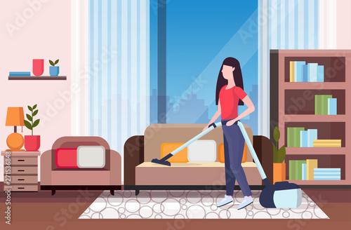 housewife using vacuum cleaner girl vacuuming couch doing housework housekeeping cleaning service concept modern living room interior full length flat horizontal