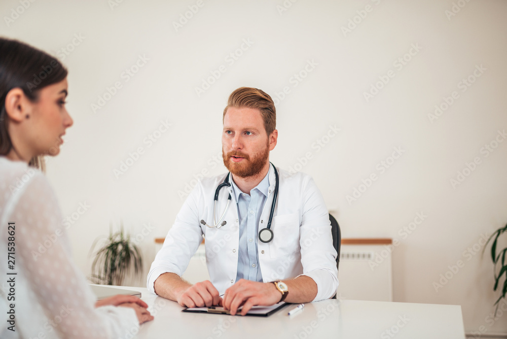 Young redhead doctor talking to a female patient in the office. Young redhead doctor talking to a female patient in the office.