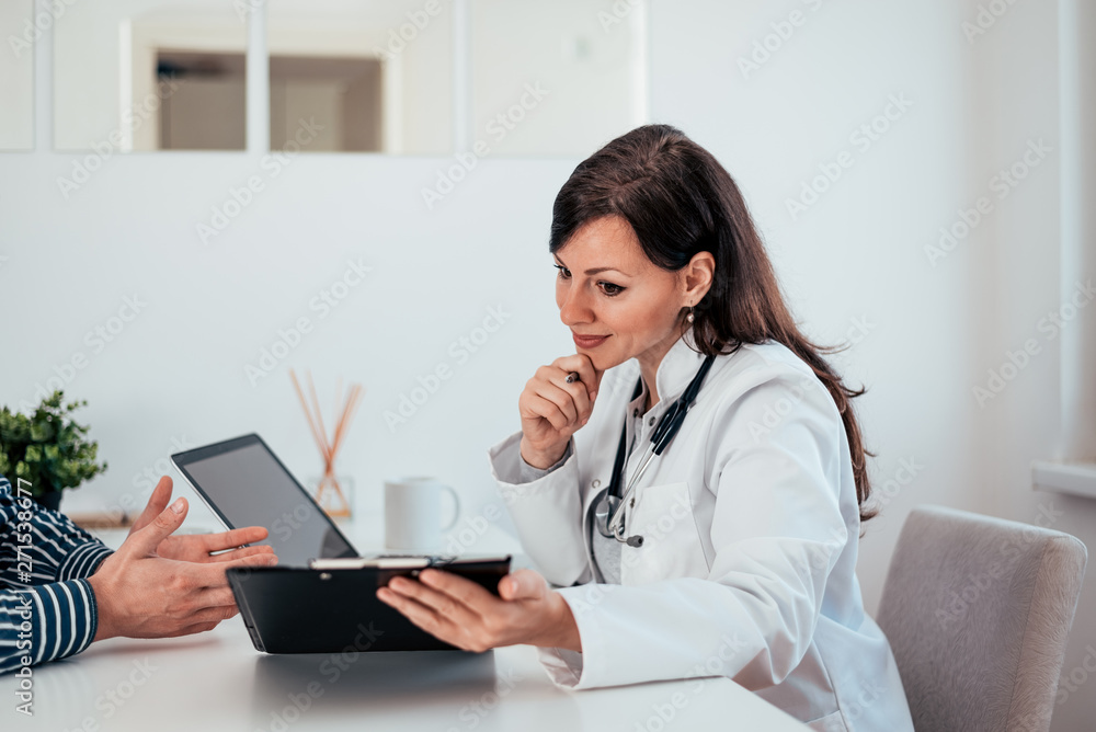Portrait of a female doctor looking at test results and talking with a patient. Portrait of a female doctor looking at test results and talking with a patient.