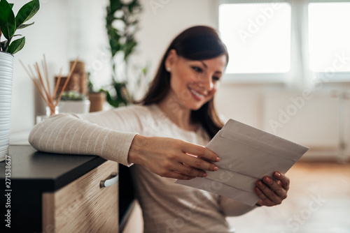 Cheerful woman checking received mail at home, focus on a mail. photo