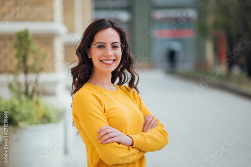 Portrait of a young confident woman outdoors, smiling at camera.