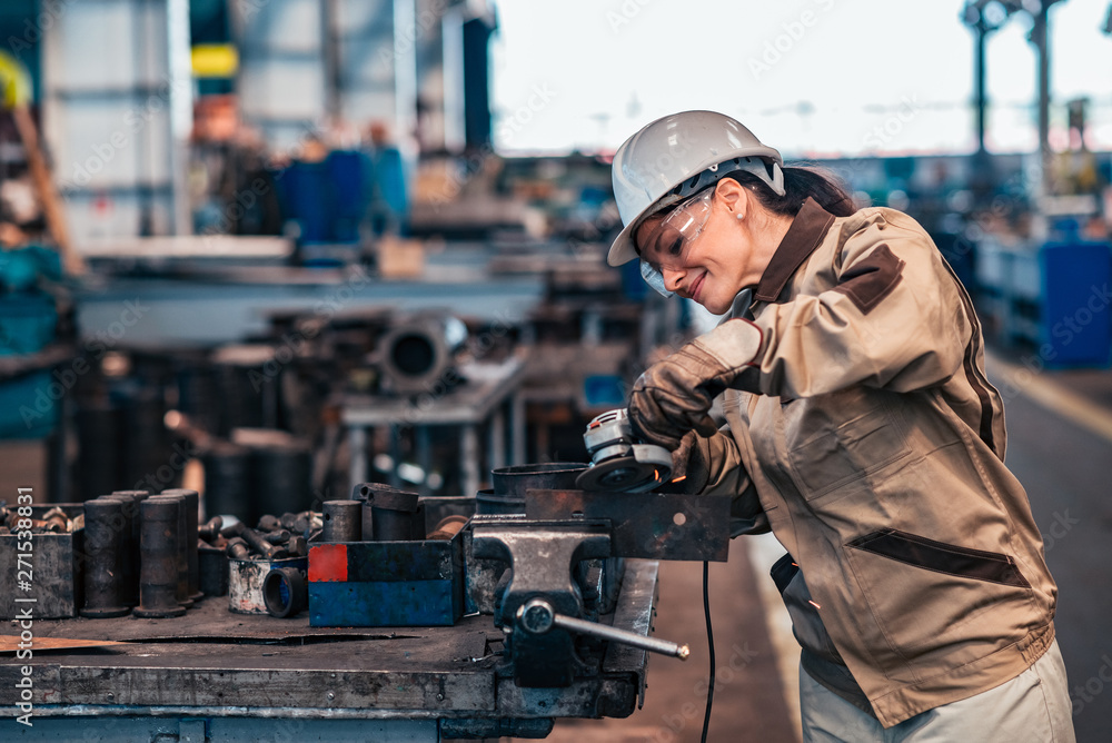 Beautiful female factory worker working with grinder and metal. Beautiful female factory worker working with grinder and metal.