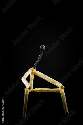 image of a man made of matchstick. Small and depressive in the dark, erased and losing the flame. Concept of weakness or sadness.