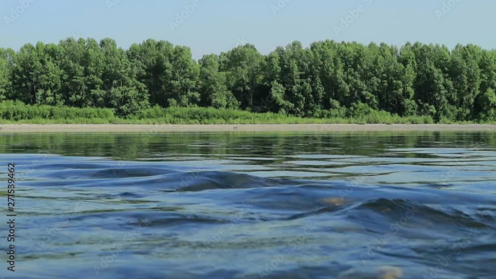 fast flow in the wide shallow river, view on a stones at the bottom through the water. sun glare on water fast flow in the wide shallow river, view on a stones at the bottom through the water. sun glare on water