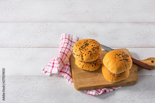 stack of bread buns on wooden cutting board on white wooden table background