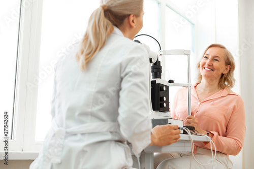 Beaming satisfied woman discussing state of her vision with educated doctor