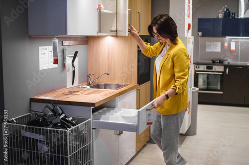 The planning of the kitchen. Young woman housewife chooses kitchen furniture to buy in the store. The concept of sales photo