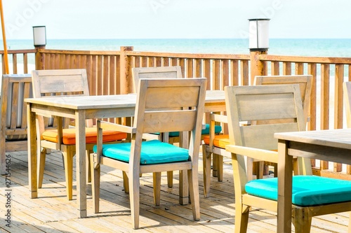 Woods tables and chairs in lounge beside sea view. © Sptgallery
