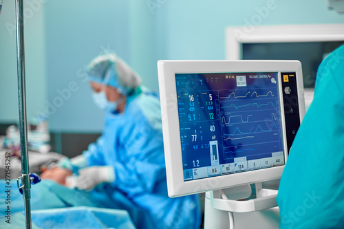 Electrocardiogram in hospital surgery operating emergency room showing patient heart rate with blur team of surgeons background photo
