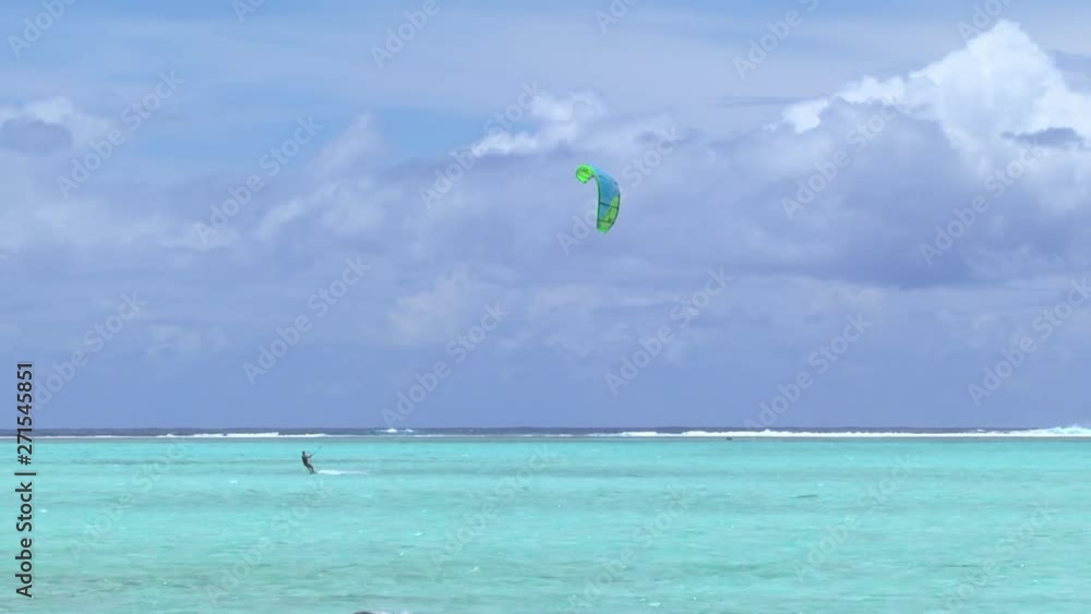 Wide angle view of Kite surfer with sail in the air riding the waves in French Polynesia Wide angle view of Kite surfer with sail in the air riding the waves in French Polynesia