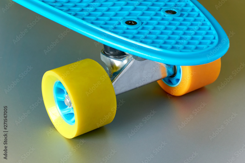 Detail of blue plastic mini cruiser penny board or skate board with yellow  and orange wheels and metal attachment on shiny metal grey background.  Stock Photo | Adobe Stock