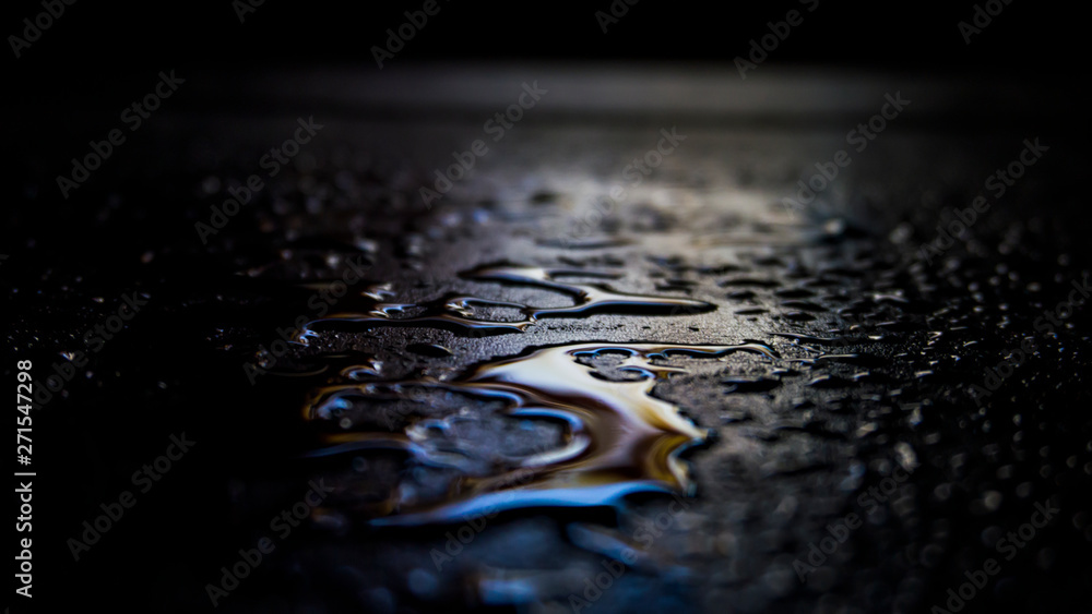 Dark background. Spilled liquid on the mirror surface, the reflection of neon lights, glare, blurred bokeh background. Neon, night view of the streets of a big city. Dark background. Spilled liquid on the mirror surface, the reflection of neon lights, glare, blurred bokeh background. Neon, night view of the streets of a big city.