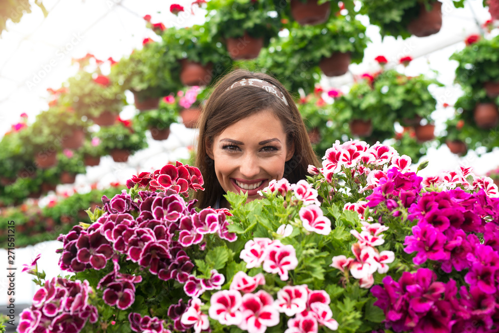 Close up view of beautiful adorable caucasian woman florist face surrounded by flowers in greenhouse garden. Close up view of beautiful adorable caucasian woman florist face surrounded by flowers in greenhouse garden.