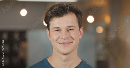 Portrait of young smiling successful businessman standing in modern office. Close up.