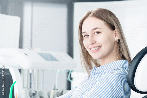 Portrait of an attractive smiling girl blonde in a dental chair. Happy customer dental cabinet