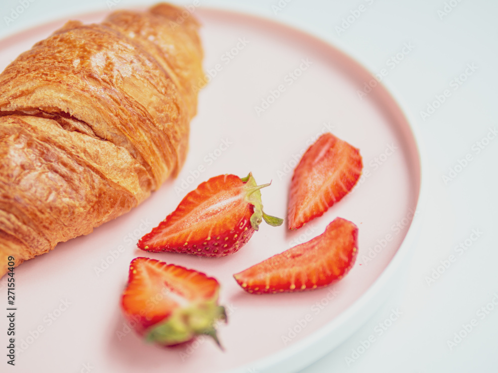 Summer breakfast. Pink plate with croissants and strawberry. Close Up