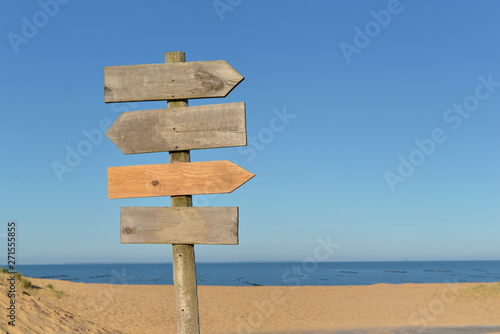 wooden signs on a post in a beach under blue sky