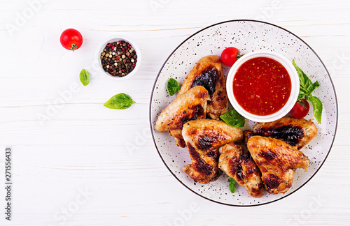 Baked chicken wings in the Asian style and tomatoes sauce on plate. Top view