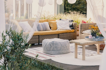 Terrace design idea with rattan garden furniture set and cozy pillows and rug, real photo