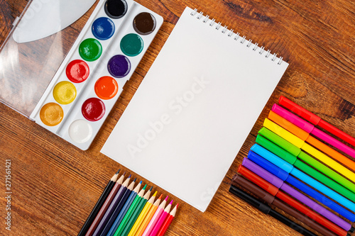 colorful pencils, markers and watercolor composition mock-up Back to school concept with stationery office supplies on a brown wooden background with copy space top view