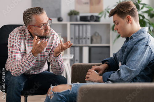 Professional counselor and troubled teenager during therapy meeting