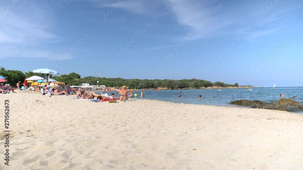 Pan over busy tourist beach in Sardinia . We see a stretch of sand and people and sea on the horizon. Pan over busy tourist beach in Sardinia . We see a stretch of sand and people and sea on the horizon.
