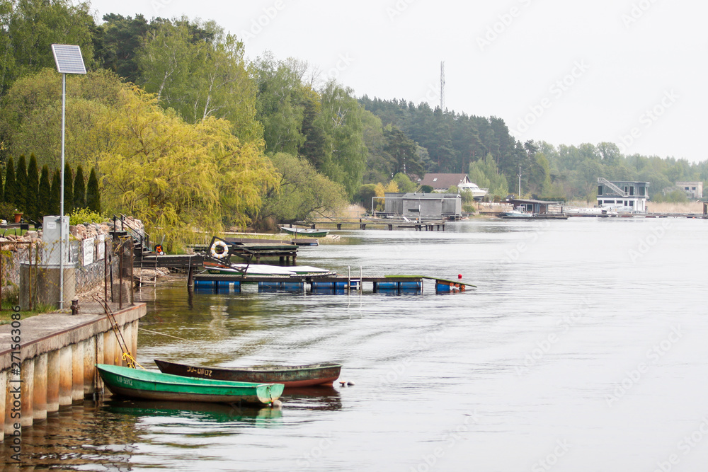 Fototapeta premium Beautiful water view on a cloudy day in a small port city with boats and bridge.