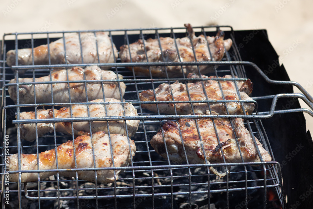 Grilled parts of chicken on the grill cooking on smoldering coal outdoors