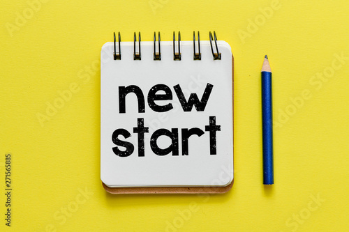 New start. Notepad with new start lettering on yellow background.