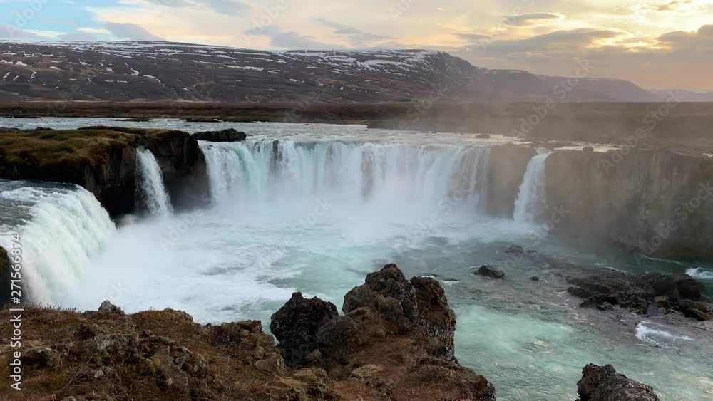 The extremely popular waterfall Godafoss filmed from the tourist plateau on a magical evening with dramatic colours in the sky and the snowcovered mountains surrounding the waterfall The extremely popular waterfall Godafoss filmed from the tourist plateau on a magical evening with dramatic colours in the sky and the snowcovered mountains surrounding the waterfall