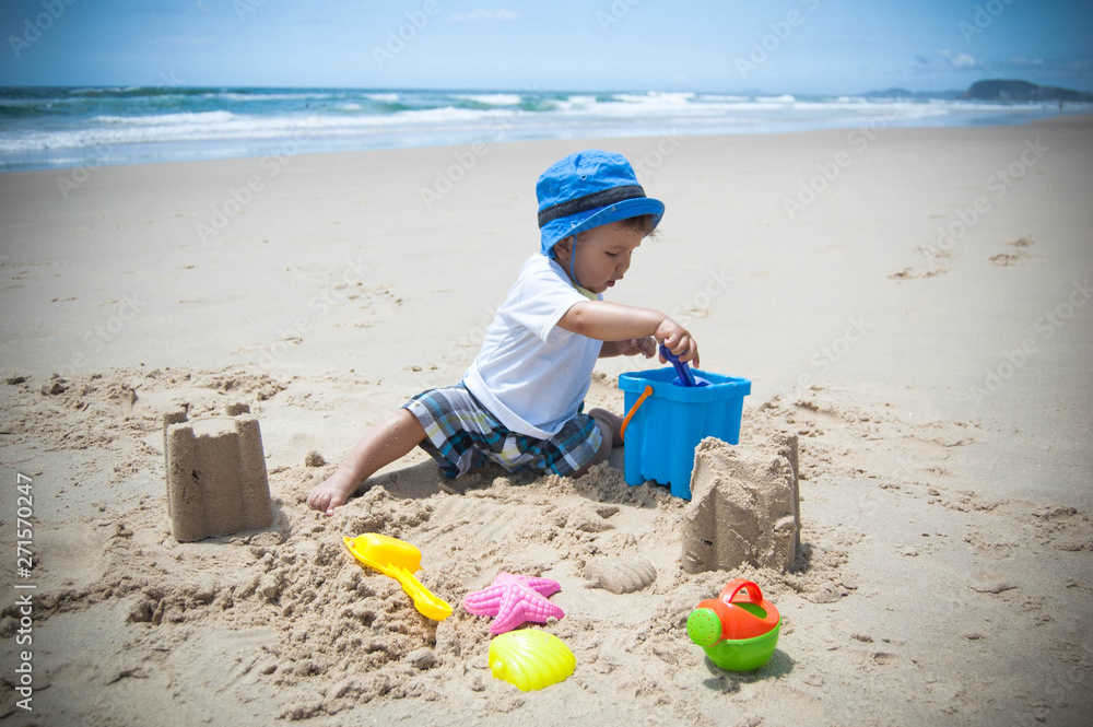 A child (baby boy) playing on a beach with sand and toys A child (baby boy) playing on a beach with sand and toys