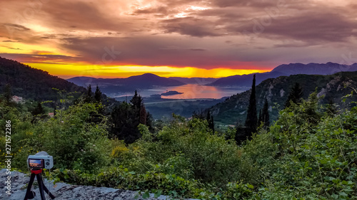 Camera capturing sunset shot. Photography using on tripod against sun rays with mountain in beautiful sundown scene.