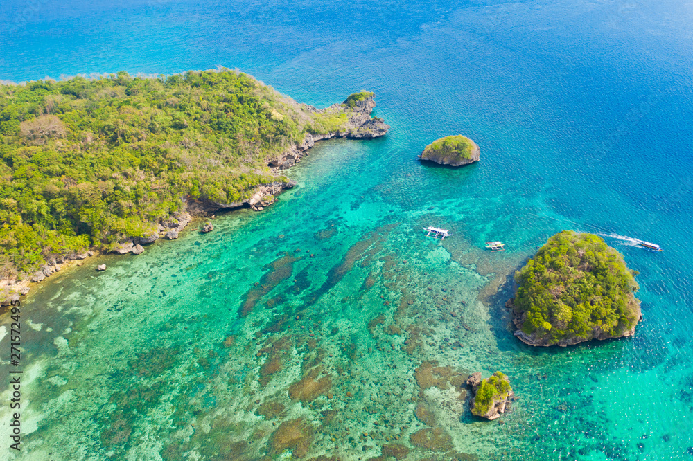 Small rocky island in the blue lagoon, view from above. Bay with turquoise water and coral bottom.