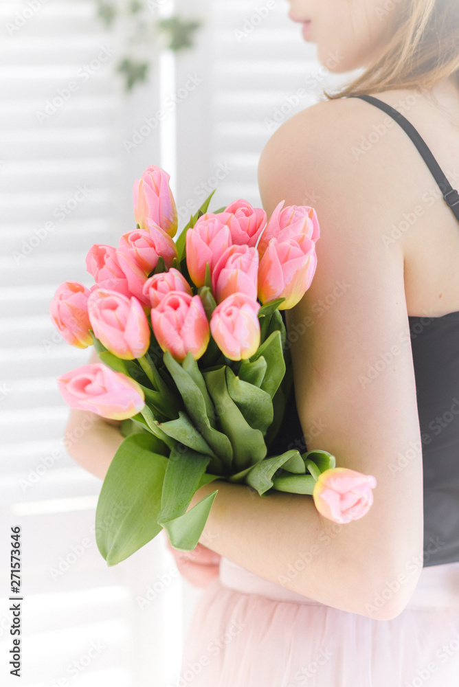 In the hands of the girl a gift, a bouquet of pink tulips. Romance and love