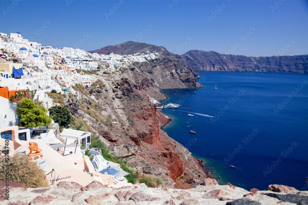 beautiful Oia town on Santorini island, Greece. Traditional white architecture and greek orthodox churches with blue domes over the Caldera, Aegean sea. Scenic travel background