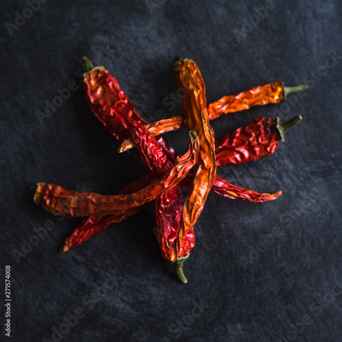 Dried red hot chili peppers on black background - concept of Asian and Mexcan spicy cuisine.