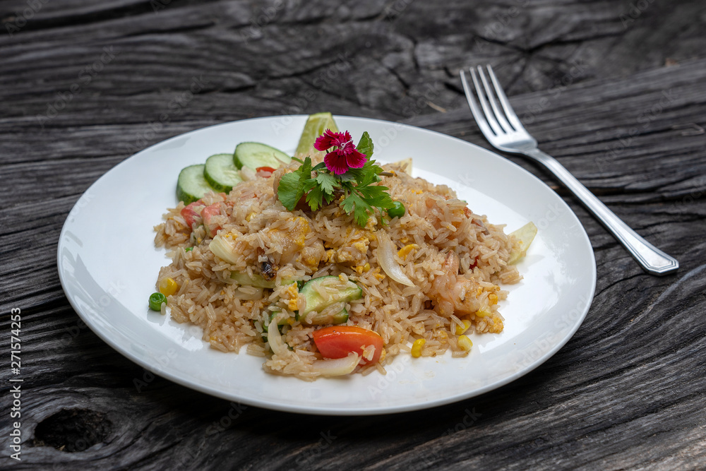 Fried rice with shrimps and vegetables in a white dish on an old wooden table, close up . Thai food , Thai cuisine Fried rice with shrimps and vegetables in a white dish on an old wooden table, close up . Thai food , Thai cuisine