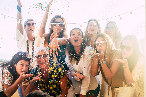 Photographie Group of people celebrate together having a lot of fun blowing coloured confetti