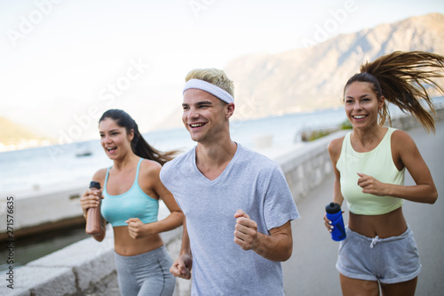 Happy fit people running and jogging together in summer sunny nature