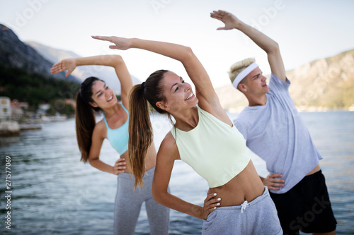 Group of happy friends or sportsmen exercising and stretching outdoor